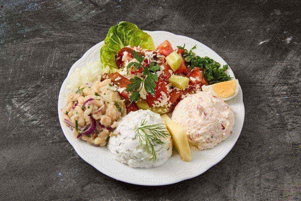 Teller mit bulgarischen Vorspeisen: Shopska-Salat, Bohnen-Salat, Schneewittchen-Dip, pikante Käsecreme und frische Kräuter